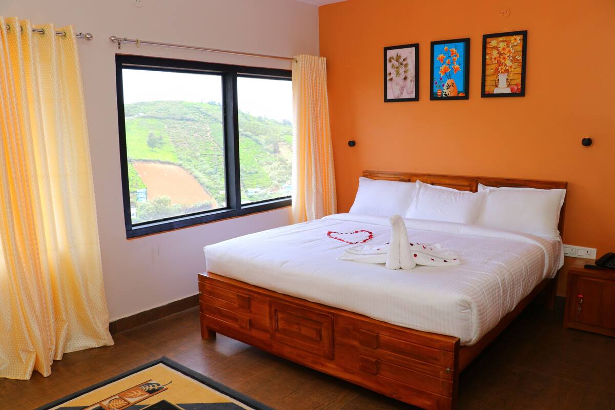 A bedroom with a large bed, a window with curtains, and three framed pictures on the wall.