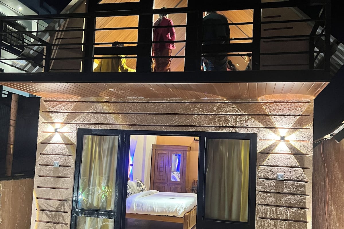 A two-story house with a balcony, a bedroom with a bed and curtains, and a sliding glass door.