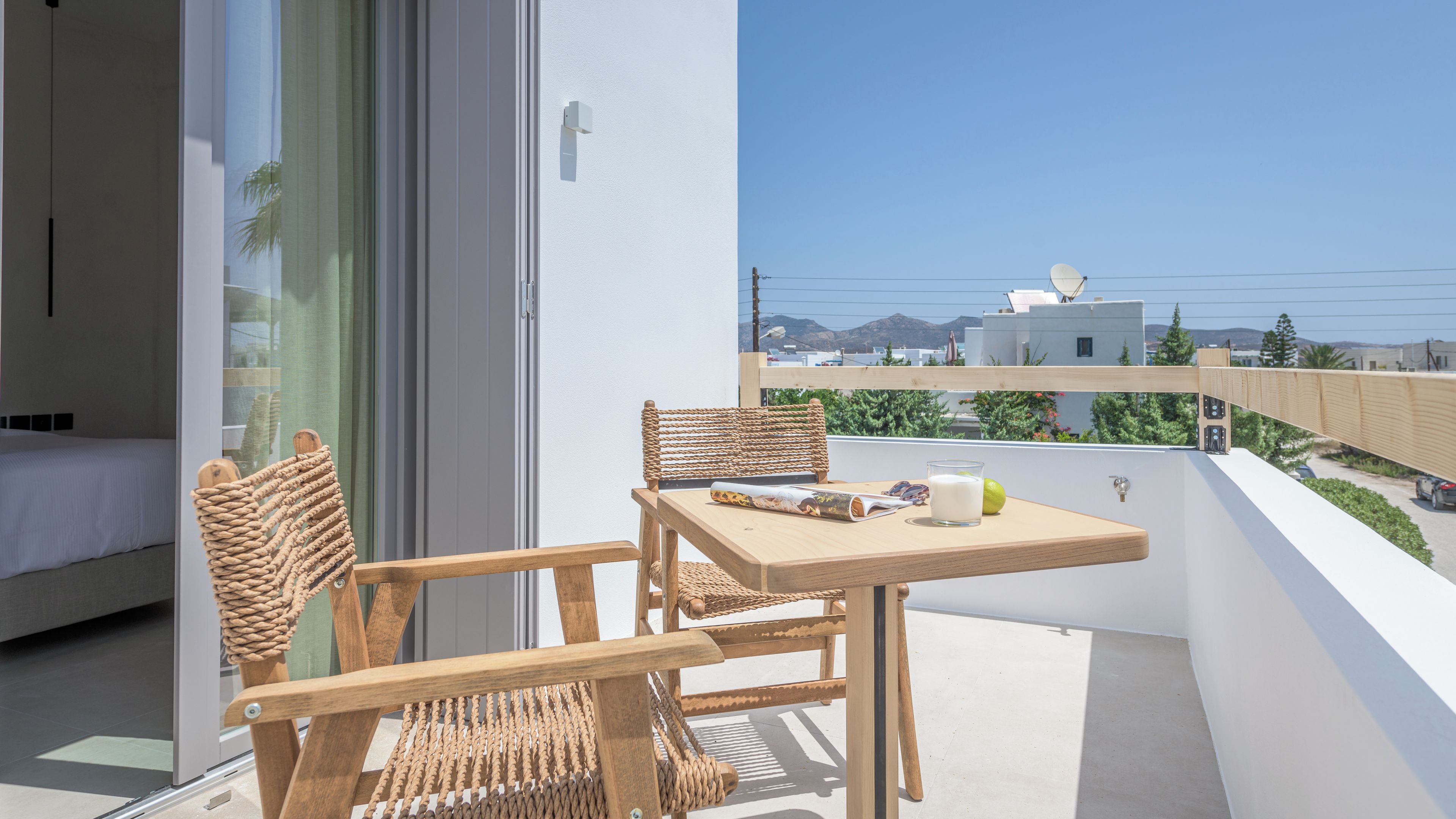 Un balcone con mobili in vimini, un tavolo e un bicchiere di latte.