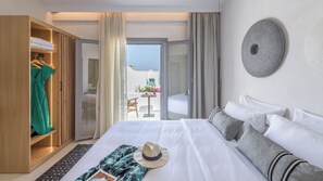A hotel room with a bed, a wardrobe, a balcony with a view, and a round wall decoration. - Nove Milos Luxury (Milos)