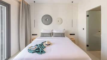A modern hotel room with a large bed, two bedside tables, a wall-mounted light, and a door with a glass panel.