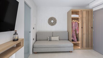 Um espaço de estar moderno e compacto, com um sofá cinzento, um guarda-roupa de madeira e um objeto decorativo fixado na parede.