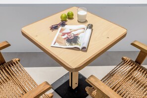 Ein Holztisch mit einer Zeitschrift, zwei grünen Äpfeln, einem Glas Milch und einer Sonnenbrille.