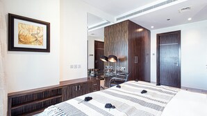Una habitación de hotel moderna con una cama grande, un escritorio con silla, un armario y una obra de arte enmarcada en la pared.