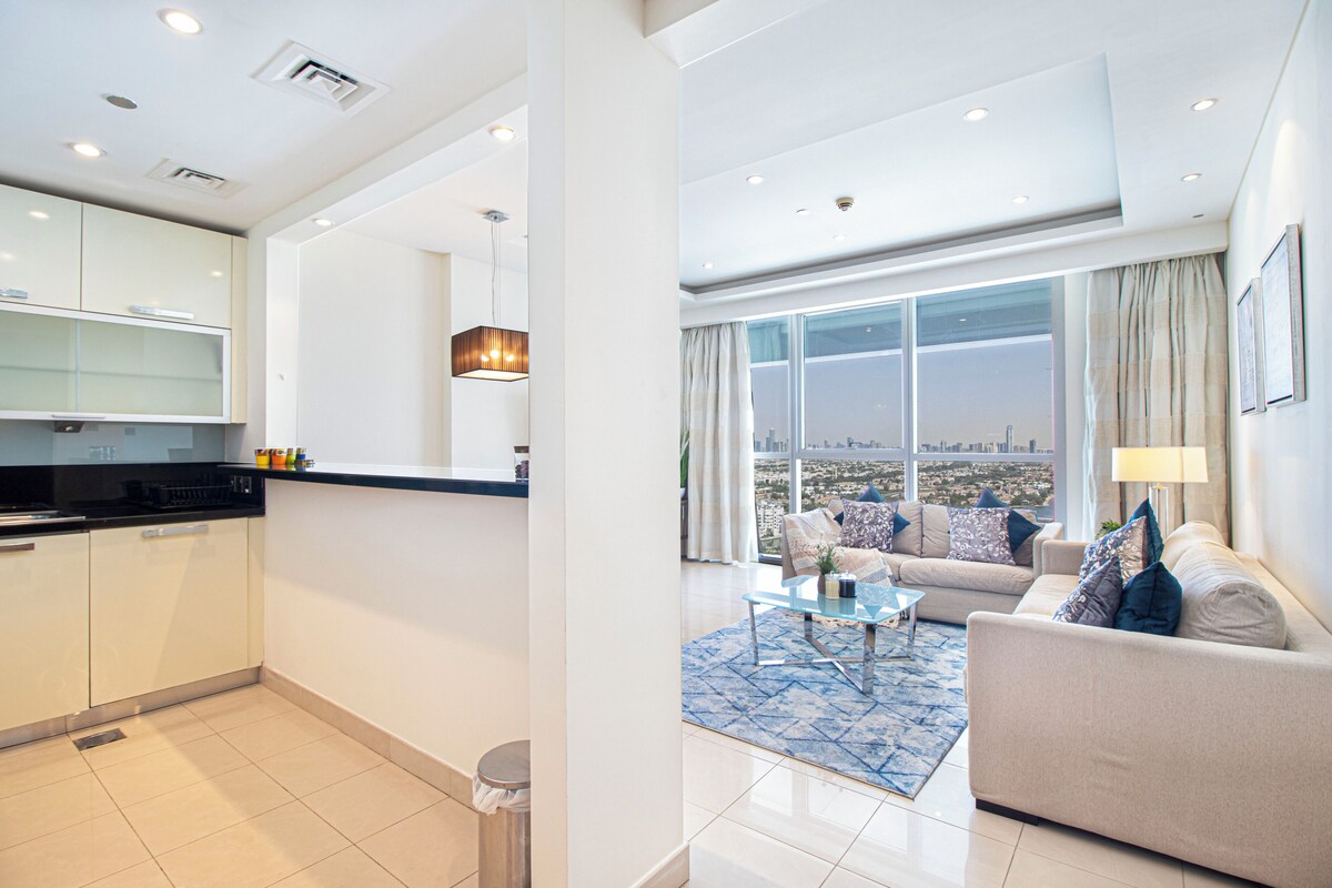 A modern apartment with a kitchen, living area, and large windows offering a city view.
