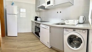 A compact kitchen with a dishwasher, microwave, and washing machine. - Balaia Plaza Al (Albufeira)