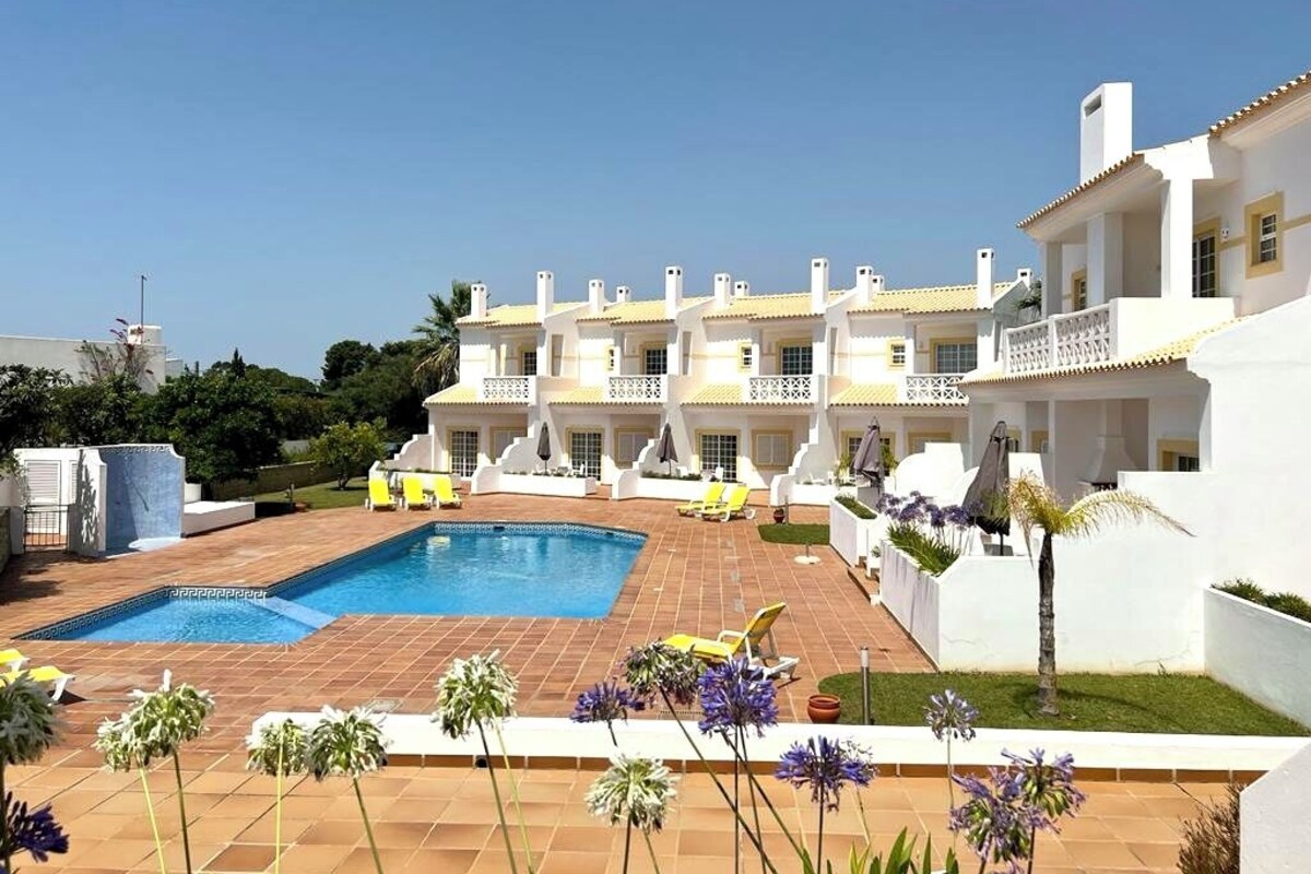A hotel with a swimming pool, multiple balconies, and a garden area.