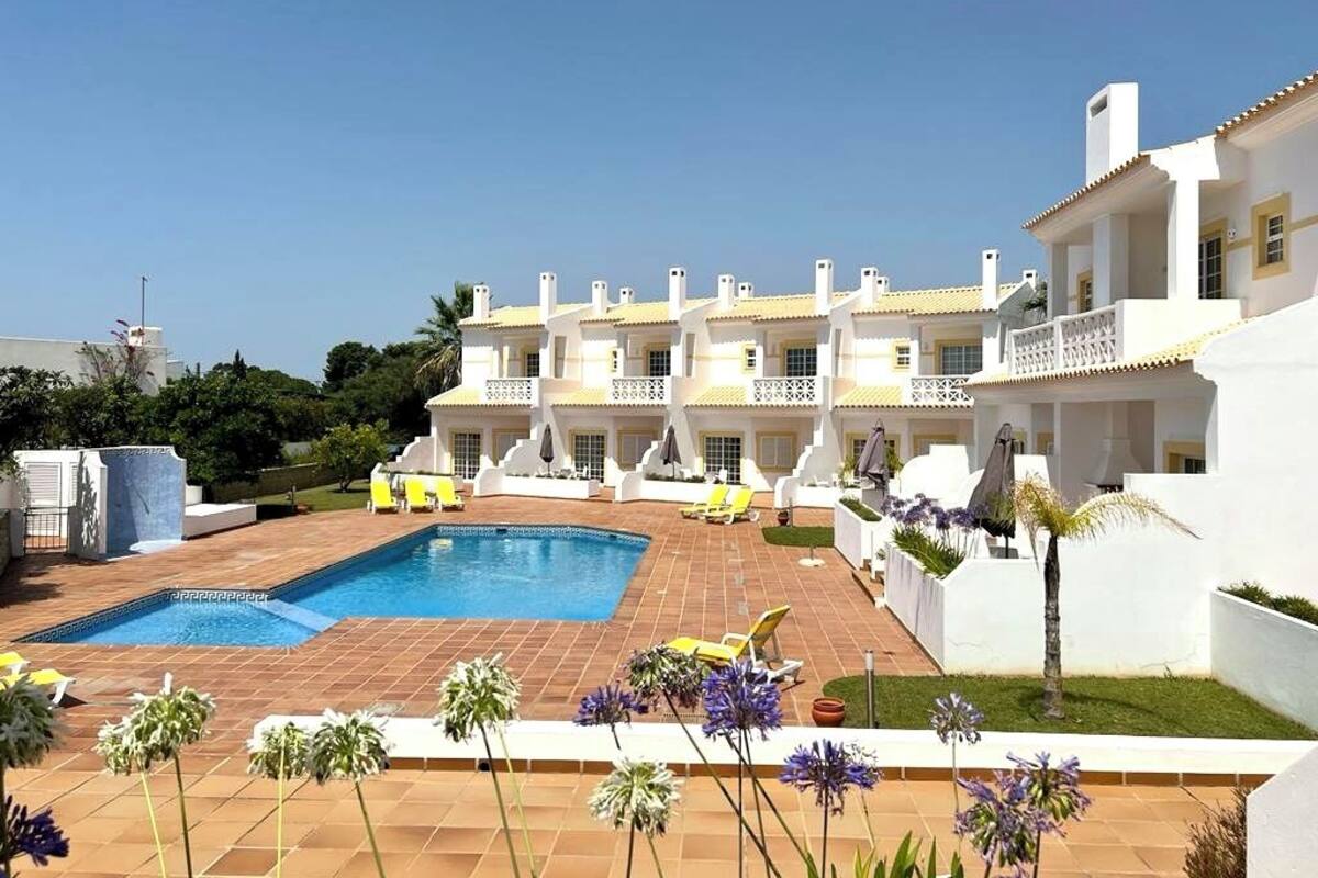 A hotel with a swimming pool, multiple balconies, and a garden area.