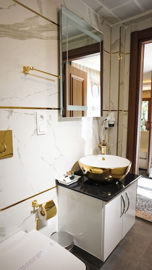 A bathroom with a marble wall, a gold sink, and a mirror. - Ayder Hasimoglu Otel - Eur (Çamlıhemşin)
