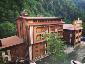 A multi-story building with a red roof, balconies, and a sign indicating a restaurant. - Ayder Hasimoglu Otel - Eur (Çamlıhemşin)