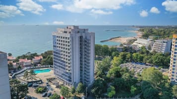 Un hotel moderno alto con piscina, rodeado de vegetación y una playa.