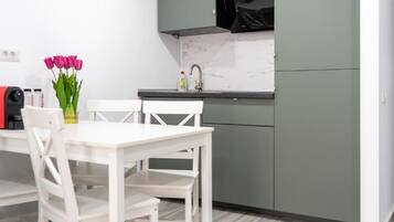 A kitchen with a white table and chairs, a vase of pink flowers, and a sink.