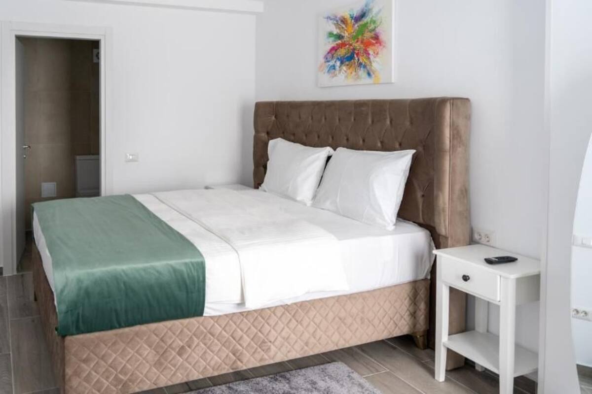 A bedroom with a bed, a bedside table, and a door leading to a bathroom.
