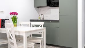 A kitchen with a white table and chairs, a vase of pink flowers, and a sink.