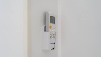 A wall-mounted electronic device, likely a thermostat or control panel, with a keypad and a small display screen.
