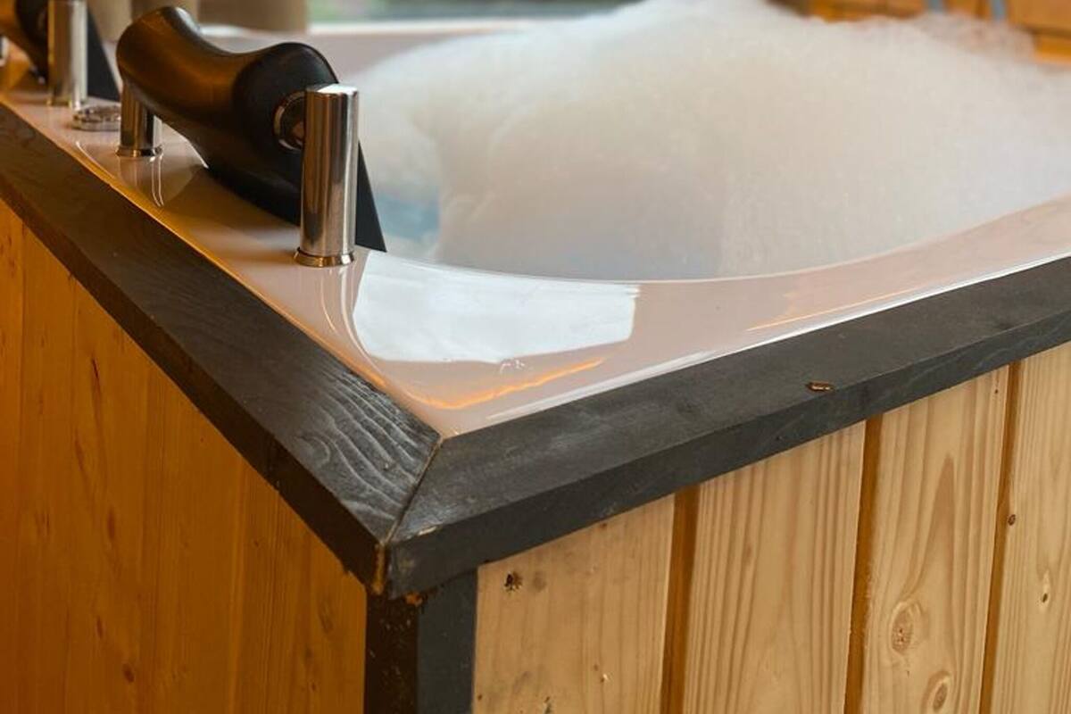Eine Holzhütte mit einem großen Fenster, einer Badewanne und einer hölzernen Bank.