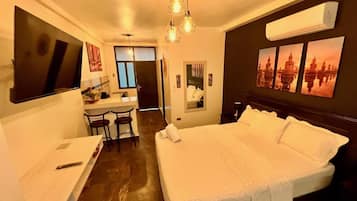Una habitación de hotel con una cama grande, un escritorio con sillas, un televisor y obras de arte en las paredes.