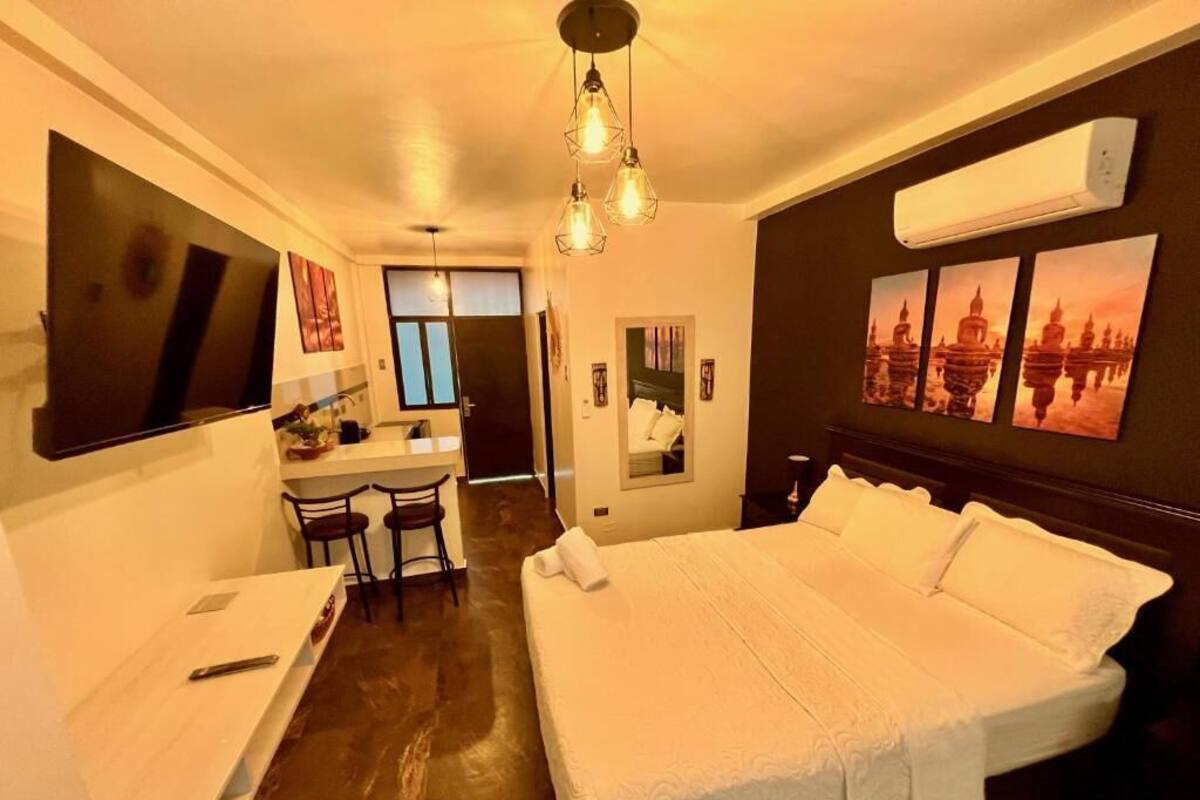 Una habitación de hotel con una cama grande, un escritorio con sillas, un televisor y obras de arte en las paredes.