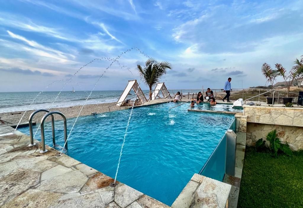 A swimming pool with a view of the ocean, a palm tree, and a person walking.