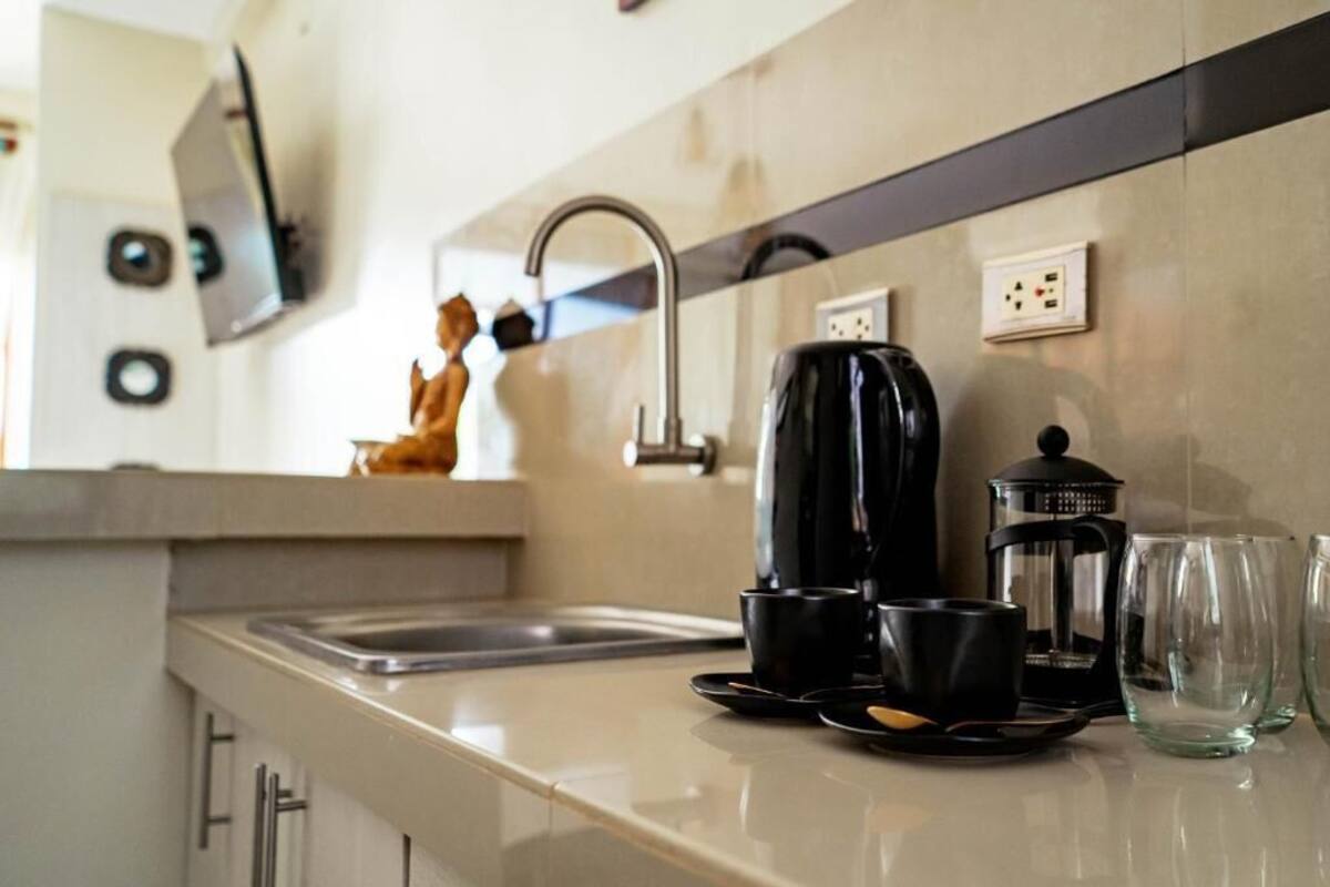 Una cocina de diseño moderno con un lavamanos, una cafetera y una jarra de vidrio.