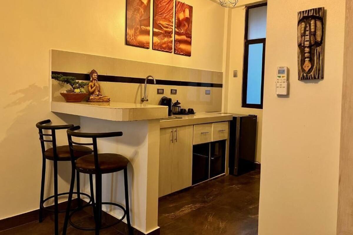 Una cocina compacta con un taburete de bar, una estatua de Buda y obras de arte en la pared.