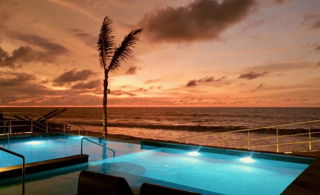 A swimming pool with a view of the ocean at sunset.