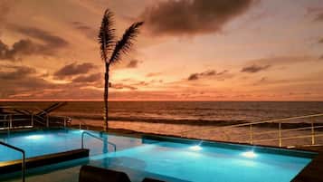 Una piscina con vista al océano al atardecer.