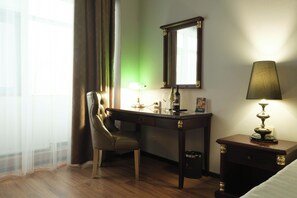 A hotel room with a desk, chair, lamp, mirror, and bedside table. - Reikartz Astana (Astana)
