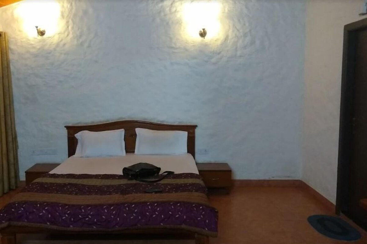 Een kamer met een bed, twee wandlampen, een nachtkastje en een deur.