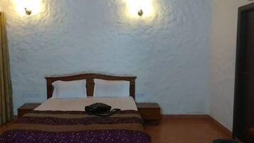 A room with a bed, two wall-mounted lights, a nightstand, and a door.