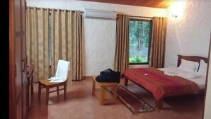 Une chambre à coucher avec un lit, une chaise, une petite table et une fenêtre avec des rideaux.