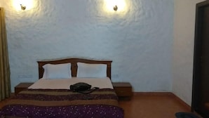 Une pièce comprenant un lit, deux lampes fixées au mur, une table de chevet et une porte.