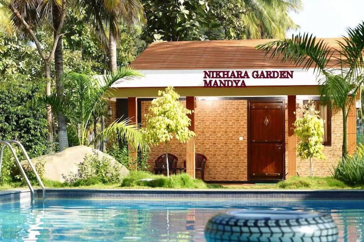 A building labeled 'Nikhara Garden Mandya' with a pool in the foreground.