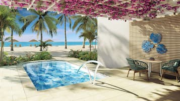 Un área de piscina con vista a la playa, sillones reclinables y una mesa con vasos.