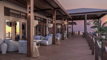 A covered outdoor area with seating, wooden beams, and hanging lights.