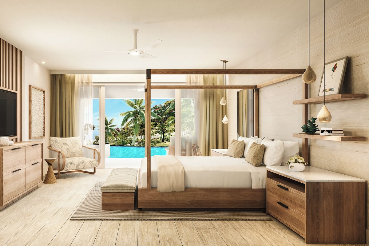 A modern bedroom with a large bed, a TV, a wooden dresser, and a view of a pool.