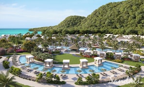 A resort with multiple swimming pools, lounge areas, and a view of the ocean.