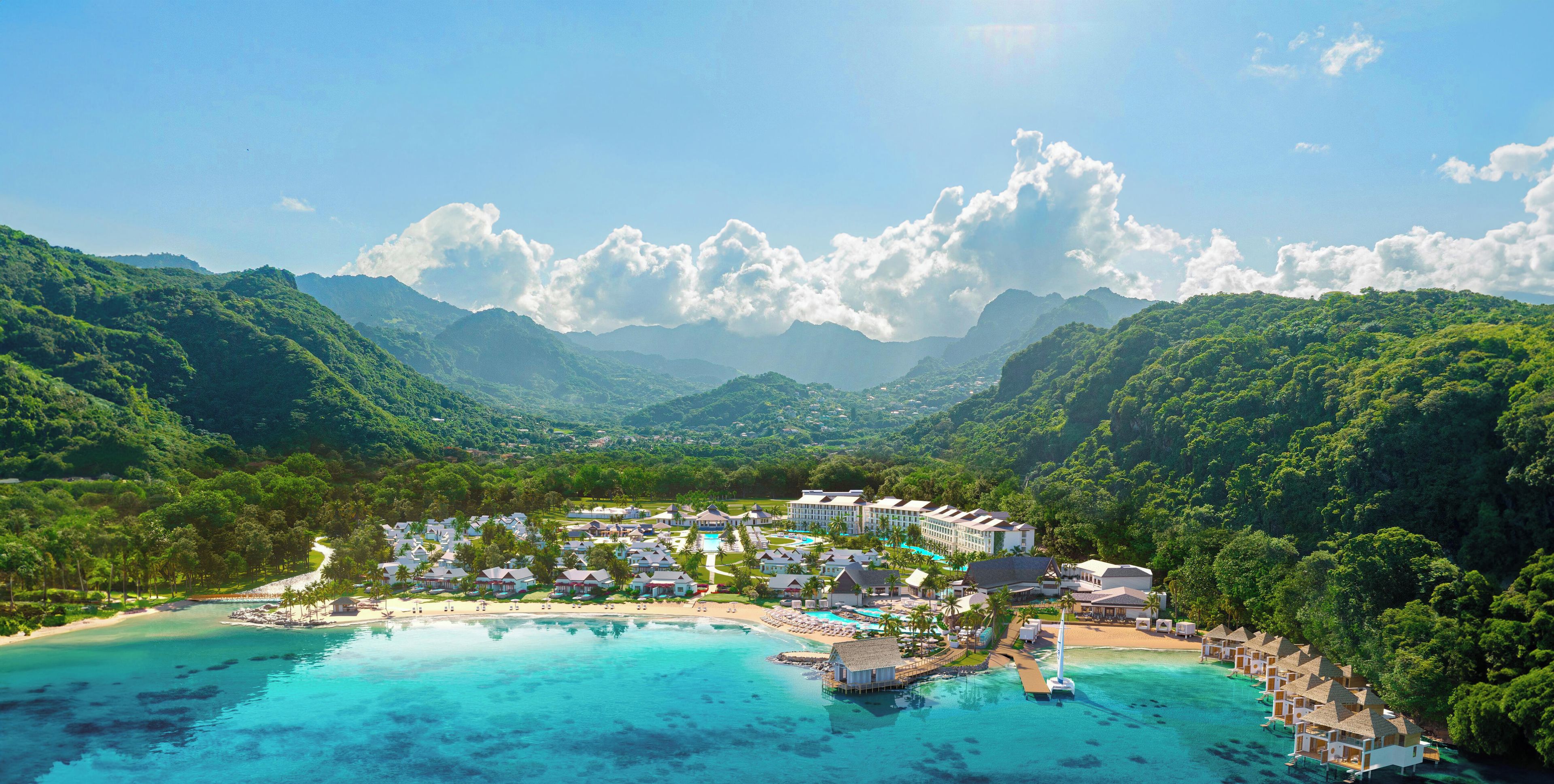 Un resort con varias construcciones, una playa y una vista despejada de las montañas circundantes.