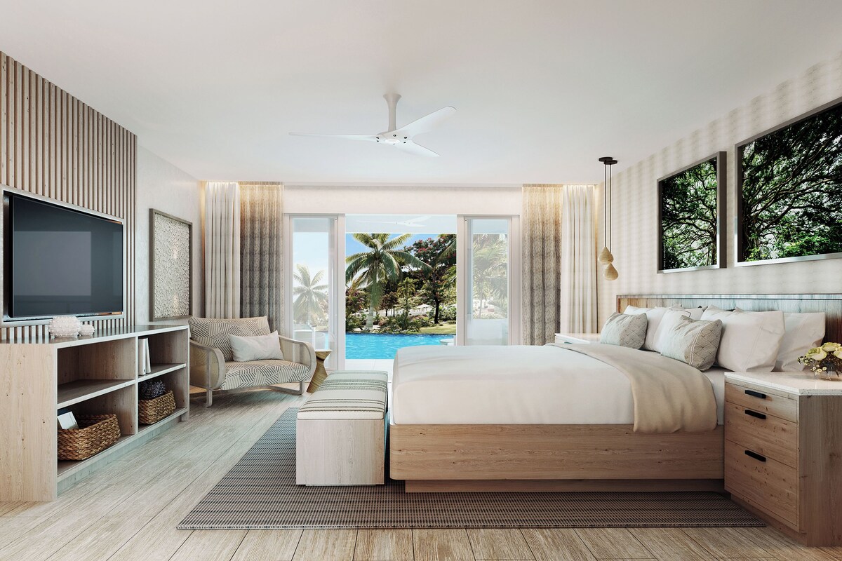 A modern bedroom with a large bed, a TV, a wooden wardrobe, and a view of a swimming pool.