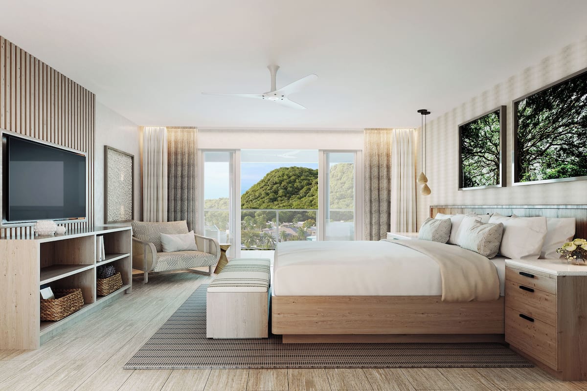 A modern bedroom with a large bed, a TV, wooden shelving, and a view of greenery.