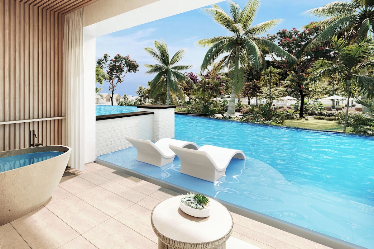 Um banheiro moderno com uma banheira independente, uma mesinha redonda com uma planta e vista para uma piscina com palmeiras.