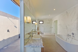 A modern bathroom with a large bathtub, a vanity with a mirror, and a shower area. - Dreamland Maldives (Hirundhoo)