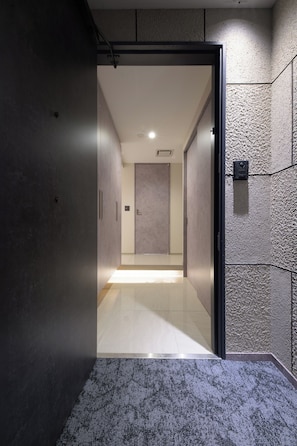 A hallway with a door leading to a room, a textured wall, and a tiled floor. - Villa Tokyo Season Ryogoku (Sumida)