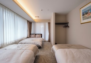 A hotel room with three beds, a headboard, a coat rack, and a framed picture on the wall. - Villa Tokyo Season Ryogoku (Sumida)