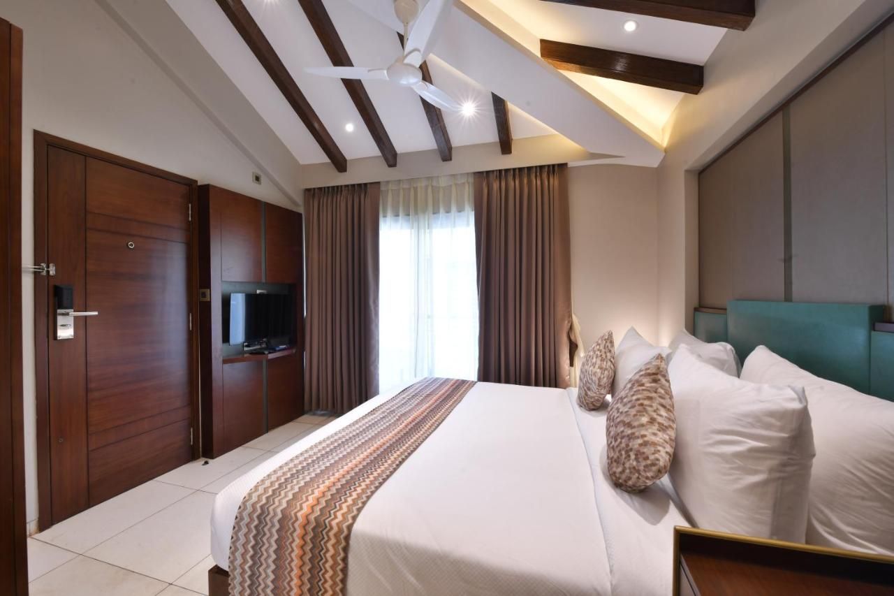 Ein Hotelzimmer mit einem großen Bett, einem Fernseher, einem Deckenventilator und einem Kleiderschrank.