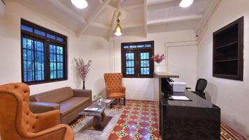 A room with a sofa, armchair, desk, and patterned floor.