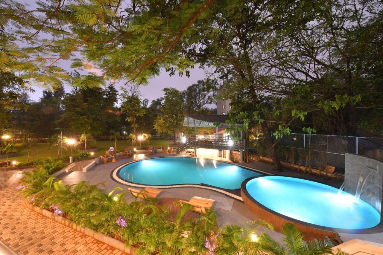 A swimming pool with a curved design, surrounded by lounge chairs and a small bridge.