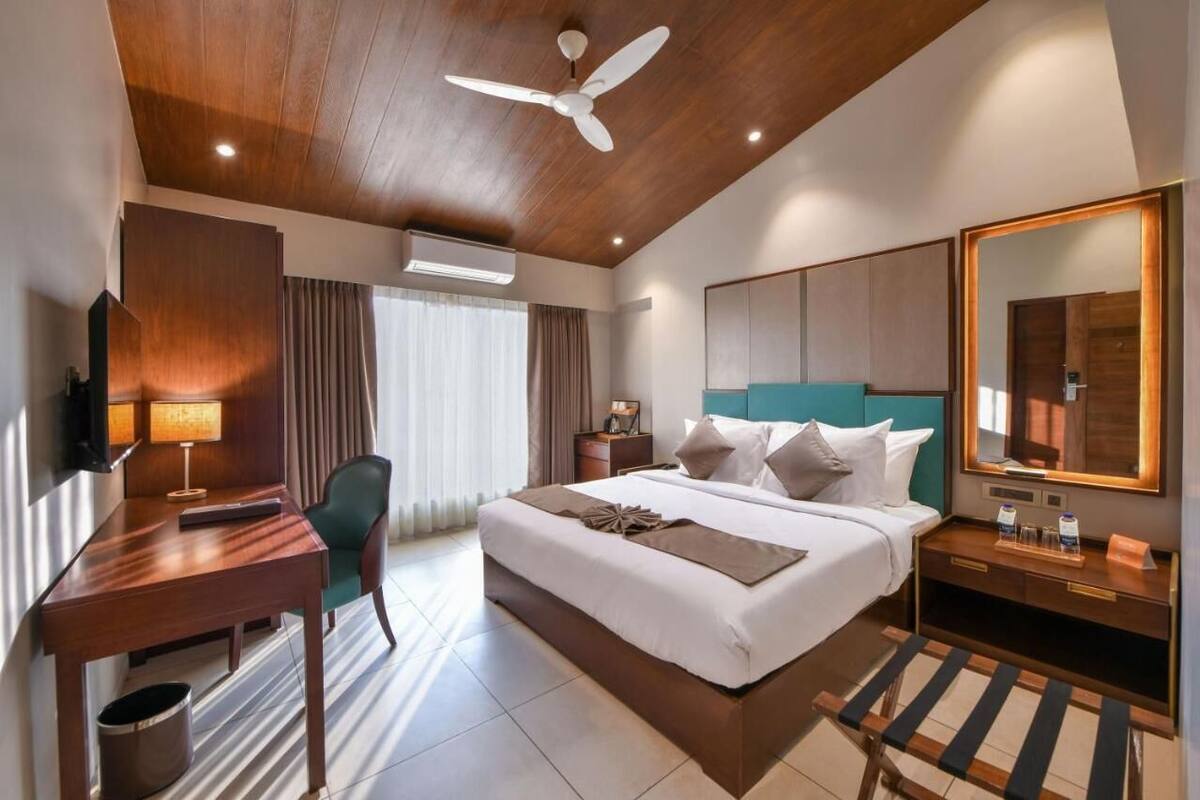 Una habitación de hotel con cama, escritorio, silla y ventilador de techo.