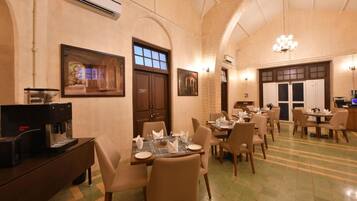 A dining area with tables set for guests, a coffee machine, and framed artwork on the walls.