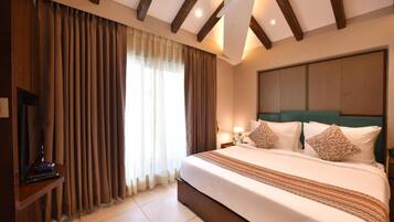 A hotel room with a large bed, curtains, a ceiling fan, and a television.